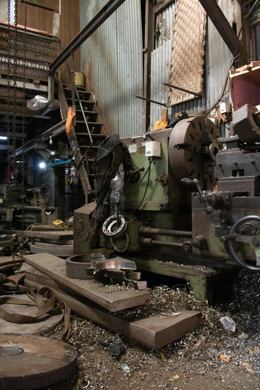 A workshop lathe with metal shavings gathered on its bed