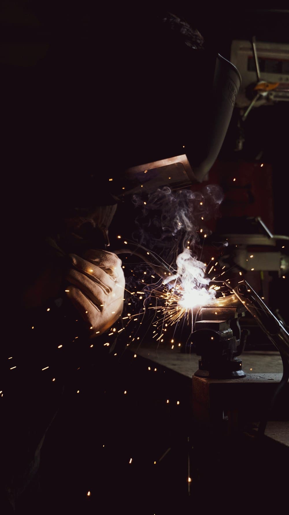 A welder working at a bench vice
